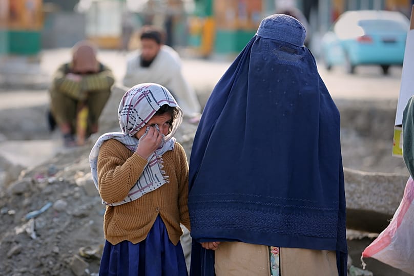 یک دختر کوچک و یک زن در حال تماشای امدادگران در حمله هوایی اواخر به یک بیمارستان ترک اعتیاد در کابل، افغانستان، سه‌شنبه، ۱۷ مارس ۲۰۲۶