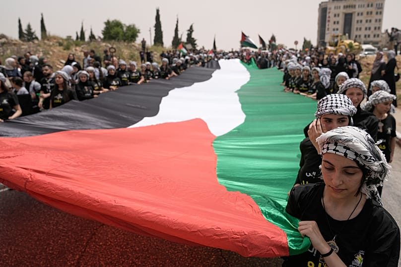 طلاب يحملون علماً فلسطينياً ضخماً خلال فعالية لإحياء الذكرى الـ78 لـ"النكبة" في رام الله، في 12 مايو 2026.