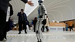 ARCHIV: Ein Besucher streckt die Hand aus, um den Roboter Unitree G1 beim Zhongguancun Forum im Zhongguancun International zu begrüßen.