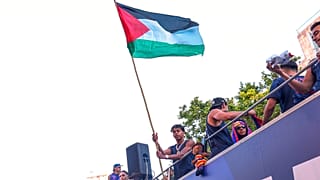 FC Barcelona player Lamine Yamal holds a Palestinian flag as he celebrates with his team atop a bus after winning the Spanish La Liga title in Barcelona,