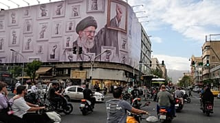 FILE - Motorbikes drive past a billboard with graphic showing the late Iranian Supreme Leader Ayatollah Ali Khamenei. 6 May 2026.