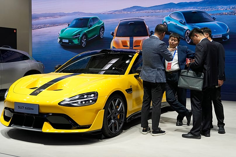 Visitors chat near a electric vehicle from Xiaomi displayed during the 2025 World Intelligent Connected Vehicles Conference in Beijing (AP Photo/Ng Han Guan) 