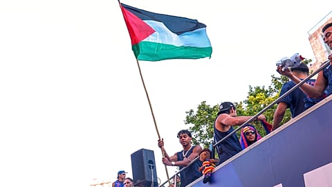 Il giocatore del FC Barcelona Lamine Yamal tiene in mano una bandiera palestinese mentre festeggia con la sua squadra in cima a un autobus dopo aver vinto il titolo della Liga spagnola a Barcellona, in Spagna, lunedì 11 maggio.
