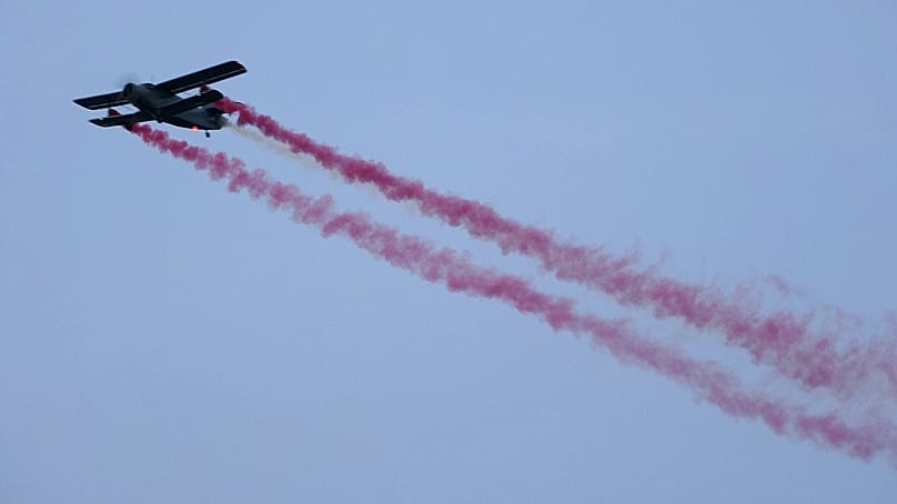 A vintage biplane paints the colors of the Latvian flag across the sky during a military parade on Latvian Independence Day, in Riga, 18 November, 2022.
