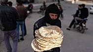 رجل يجمع الخبز من مخبز في بلدة حرستا سوريا، الخميس 9 يناير 2025.