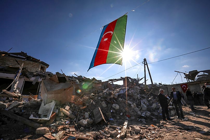 Azerbaijan's national flag flies over destroyed houses in a residential area that was hit by rocket fire overnight by Armenian forces in Ganja, 22 October, 2020