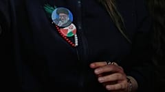 ترتدي إحدى المؤيدات للحكومة شارات تحمل صورة المرشد الإيراني الراحل علي خامنئي، إلى جانب العلمين الإيراني والفلسطيني، طهران، الأربعاء 13 مايو/ أيار 2026.