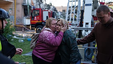 Una mujer besa a su familiar evacuado de una casa muy dañada tras un ataque ruso contra un barrio residencial de Kiev.
