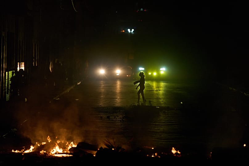 Uma mulher caminha em frente a uma barricada montada por residentes que protestam contra os prolongados cortes de eletricidade em Havana, 13 de maio de 2026