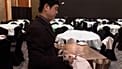 David Park, empleado del Lotte Hotel Seoul, lleva cámaras corporales mientras dobla servilletas de banquete, limpia copas y prepara una mesa.