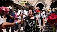 Un activista solidario entrega flores a una mujer en la Ciudad Vieja antes de la marcha de las banderas