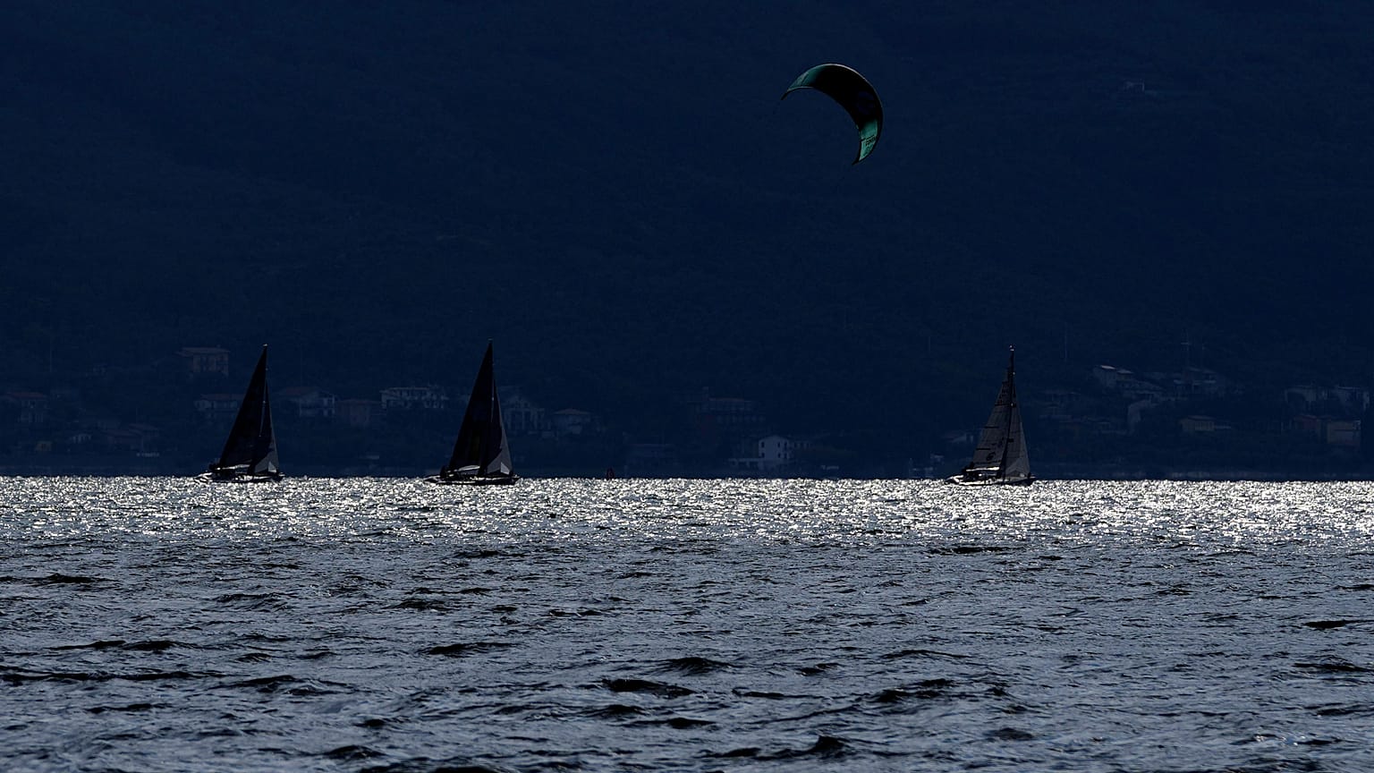Um kitesurfer passa por barcos à vela no Lago de Garda, perto de Brenzone sul Garda, no norte de Itália, no sábado, 9 de outubro de 2021.