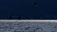Un kitesurfer passa davanti a delle barche a vela sul lago di Garda, vicino a Brenzone sul Garda, nel nord Italia, sabato 9 ottobre 2021.