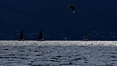 Ein Kitesurfer fährt am Samstag, den 9. Oktober 2021, auf dem Gardasee nahe Brenzone sul Garda in Norditalien an Segelbooten vorbei.