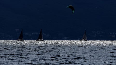 Um kitesurfer passa por barcos à vela no Lago de Garda, perto de Brenzone sul Garda, no norte de Itália, no sábado, 9 de outubro de 2021.