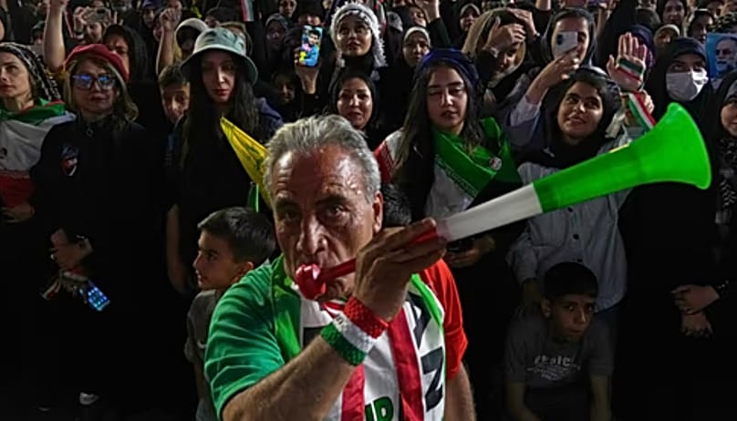 A man wearing a shirt bearing Iran's national soccer team logo blows a plastic trumpet during a pro-government gathering in support of Iran's World Cup team at Islamic Revolut