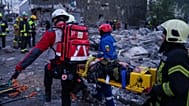 I soccorritori trasportano su una barella una donna ferita da un'abitazione danneggiata in seguito a un attacco russo contro quartiere residenziale di Kiev, 14/05/2026