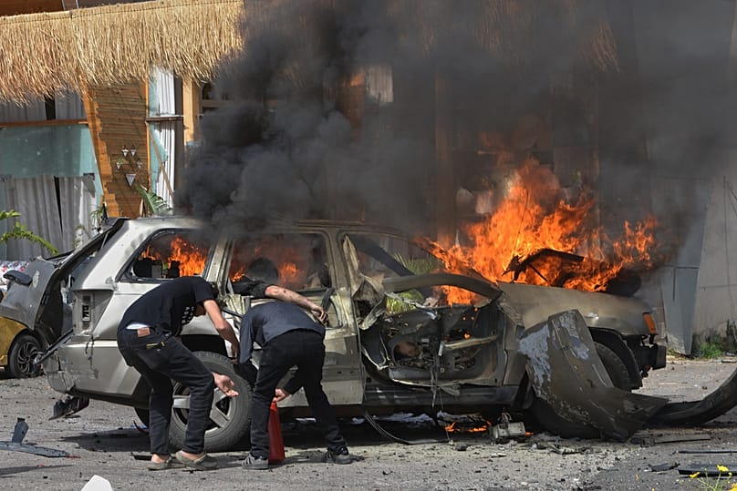 A person seen inside a burning vehicle as men attempt to put out the fire after an Israeli airstrike hit a car in Barja, south of Beirut, Lebanon. May 13, 2026.