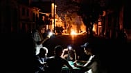 People illuminate themselves with their phones as a fire set up by residents protesting against prolonged power outages burns in Havana, 14 May, 2026
