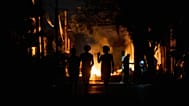 Personas caminan por la calle junto a una hoguera encendida por vecinos que protestan por los prolongados cortes de luz en una calle de La Habana
