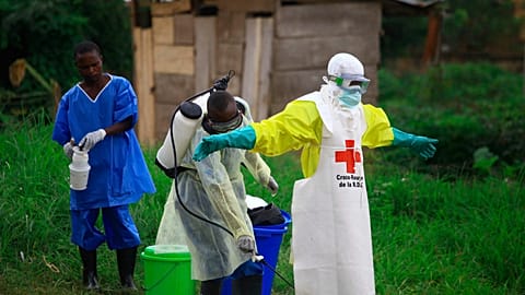 FILE - A health worker sprays disinfectant on his colleague after working at an Ebola treatment center in Beni, eastern Congo, Sept 9, 2018