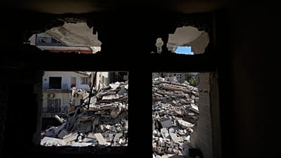 Zniszczony budynek, trafiony kilka tygodni temu izraelskim nalotem, widać przez uszkodzony dom w południowym Tyrze w Libanie, 30 kwietnia 2026 r.