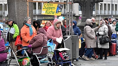 Deserving poor wait in lines behind a sign reading 'Soup Kitchen' to get free food at the old town of Cologne, Germany, Friday, Nov. 11, 2016. 