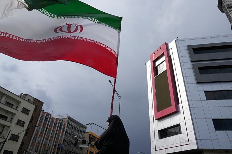A woman holds an Iranian flag during a pro-government campaign in downtown Tehran, 17 May, 2026