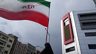 سيدة إيرانية ترفع العلم الإيراني في مظاهرة داعمة للنظام في طهران