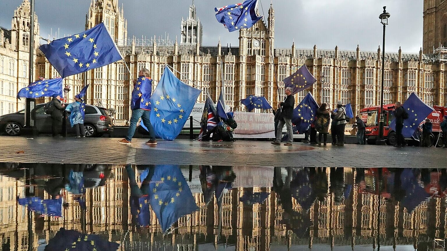 Protestors are reflected in a large puddle as they wave European flags to demonstrate against Brexit in front of the Parliament in London, Dec. 3, 2018