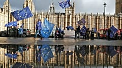 Protestors are reflected in a large puddle as they wave European flags to demonstrate against Brexit in front of the Parliament in London, Dec. 3, 2018