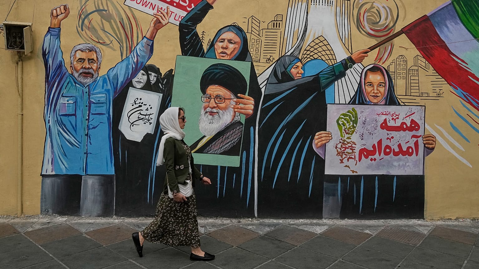 امرأة تمرّ أمام جدارية مؤيدة للحكومة في وسط مدينة طهران، طهران، الأحد 17 مايو/أيار 2026.