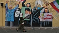 امرأة تمرّ أمام جدارية مؤيدة للحكومة في وسط مدينة طهران، طهران، الأحد 17 مايو/أيار 2026.
