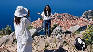 Turisti scattano foto su una collina che domina il centro storico di Dubrovnik, in Croazia, lunedì 27 aprile 2026.