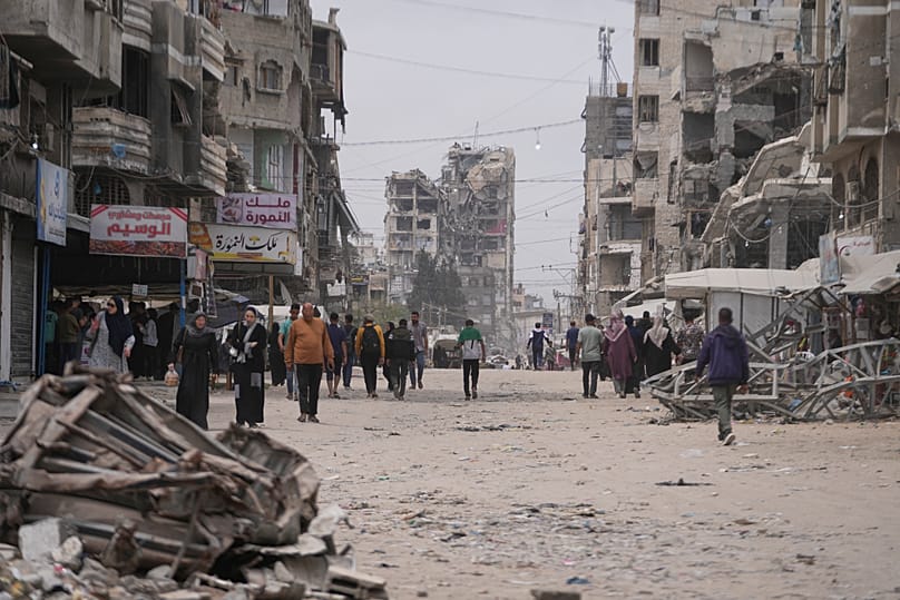 Palestinians walk along a street surrounded by buildings destroyed during the Israel Hamas war in Gaza City, 15 May, 2026