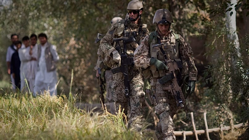Afghanische Männer beobachten Soldaten der Bundeswehr bei einer Patrouille in der Nähe von Char Darah, Afghanistan, am 20. September 2011