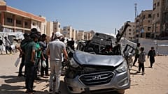 فلسطينيون يتفقدون سيارة تعرضت لغارة جوية إسرائيلية في خان يونس جنوب قطاع غزة، الأحد 10 مايو 2026.