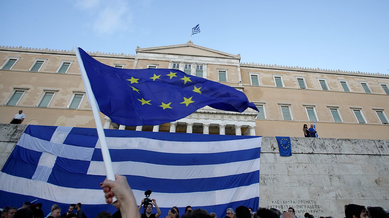A pro-Euro demonstrator waves a European Union flag outside the Greek Parliament during a rally in Athens, Monday, June 22, 2015. Thousands of people gathered to show support 