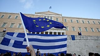 A pro-Euro demonstrator waves a European Union flag outside the Greek Parliament during a rally in Athens, Monday, June 22, 2015. Thousands of people gathered to show support 