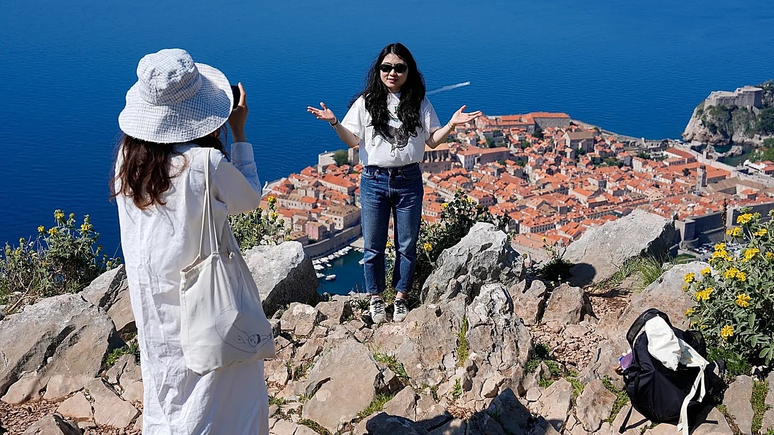 Tourists take pictures on a hill overlooking the old town of Dubrovnik in Croatia