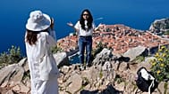 Tourists take pictures on a hill overlooking the old town of Dubrovnik in Croatia