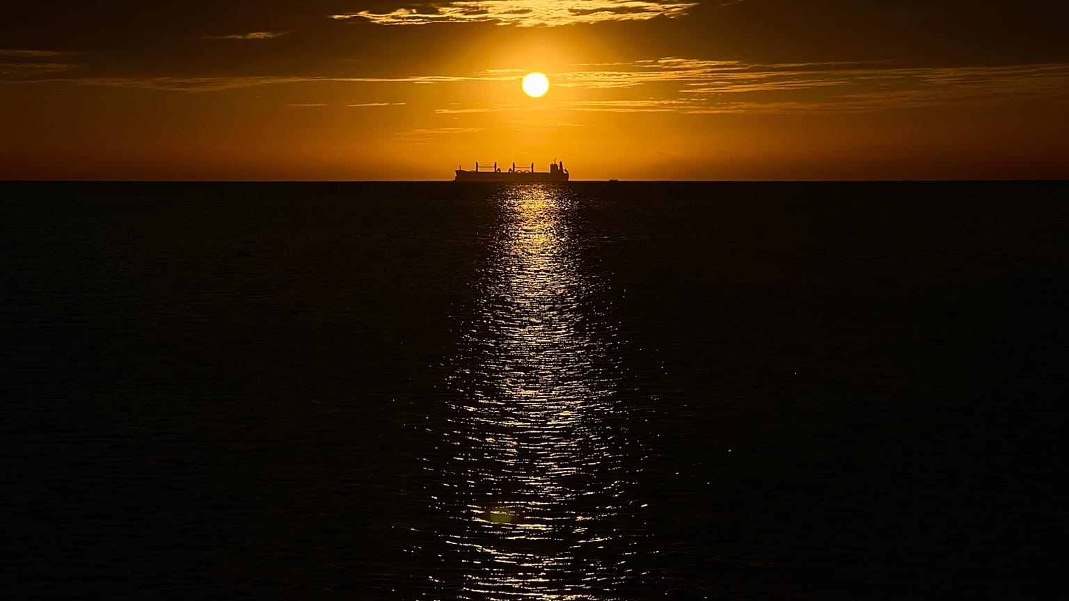 Un buque petrolero es visible en el mar Caribe al atardecer durante una conferencia cercana cuyo objetivo es la transición hacia fuentes de energía alternativas