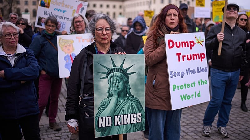 Demonstrators hold posters as they attend a No Kings Protest against the US government and President Donald Trump in Berlin, Germany, Saturday, March 28, 2026.