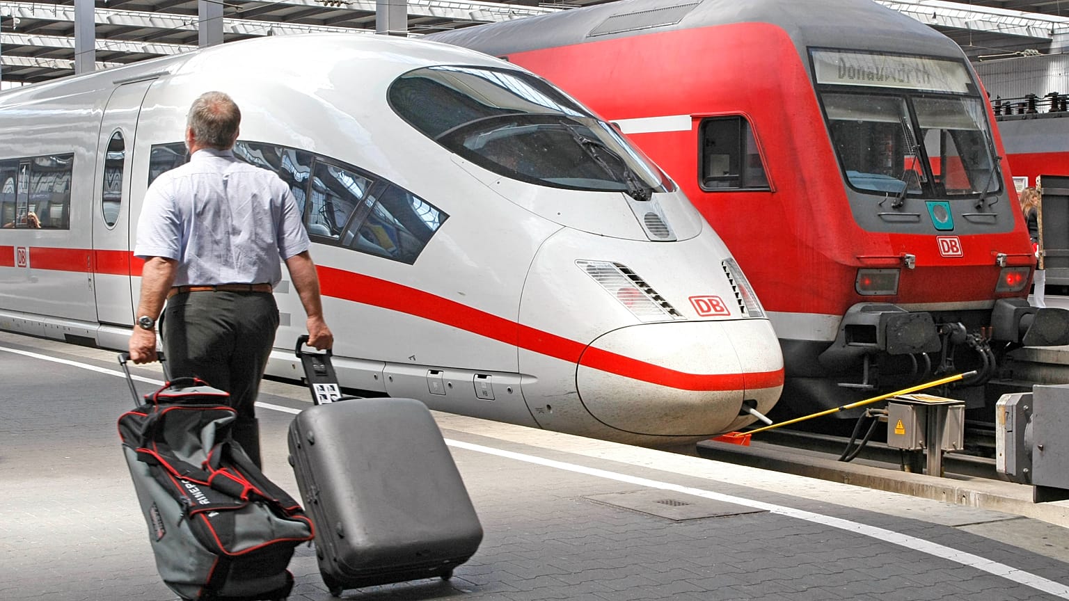 A traveller walks past an ICE and a regional train at Munich Central Station on Friday, 13 July 2007. 