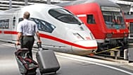 A traveller walks past an ICE and a regional train at Munich Central Station on Friday, 13 July 2007. 