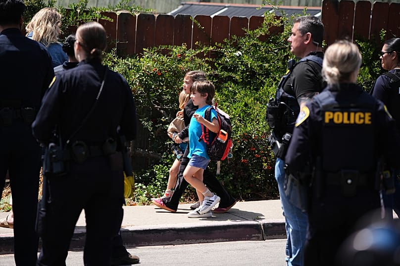 Dos niños caminan de la mano cerca del lugar de un tiroteo frente al Centro Islámico de San Diego el lunes 18 de mayo de 2026, en San Diego, California, EE.UU.