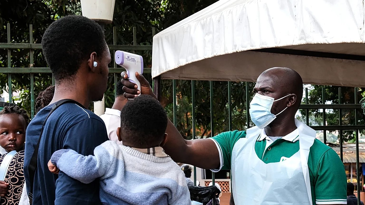 A health official uses a thermometer to screen people in front of Kibuli Muslim Hospital in Kampala, 16 May, 2026