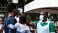 A health official uses a thermometer to screen people in front of Kibuli Muslim Hospital in Kampala, 16 May, 2026