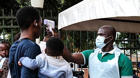 A health official uses a thermometer to screen people in front of Kibuli Muslim Hospital in Kampala, 16 May, 2026