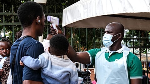 A health official uses a thermometer to screen people in front of Kibuli Muslim Hospital in Kampala, Uganda, Saturday, May 16, 2026.